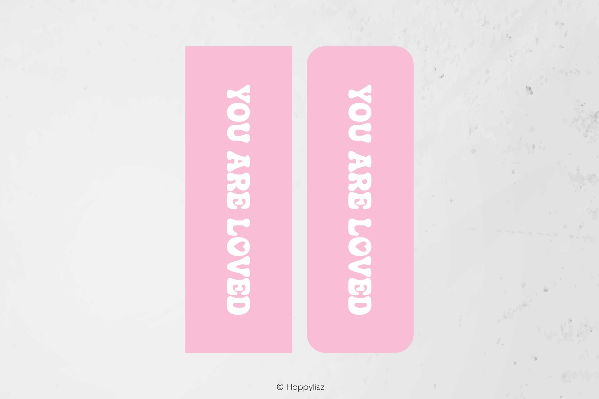 Two pink rectangular labels with rounded corners, each printed with the phrase 'YOU ARE LOVED' in white vertical text, shown on a light textured background.